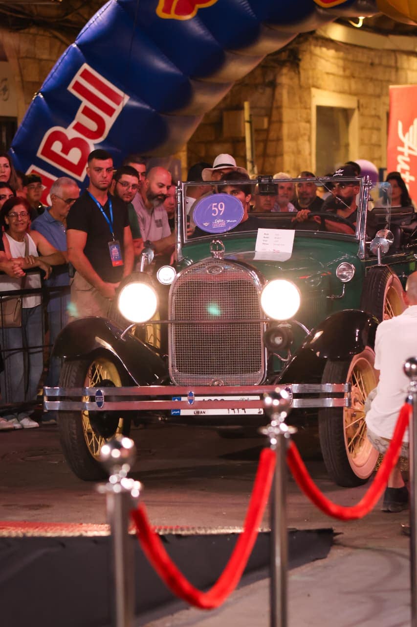 A green 1920s Ford behind the rope with the crowd pressed in around it