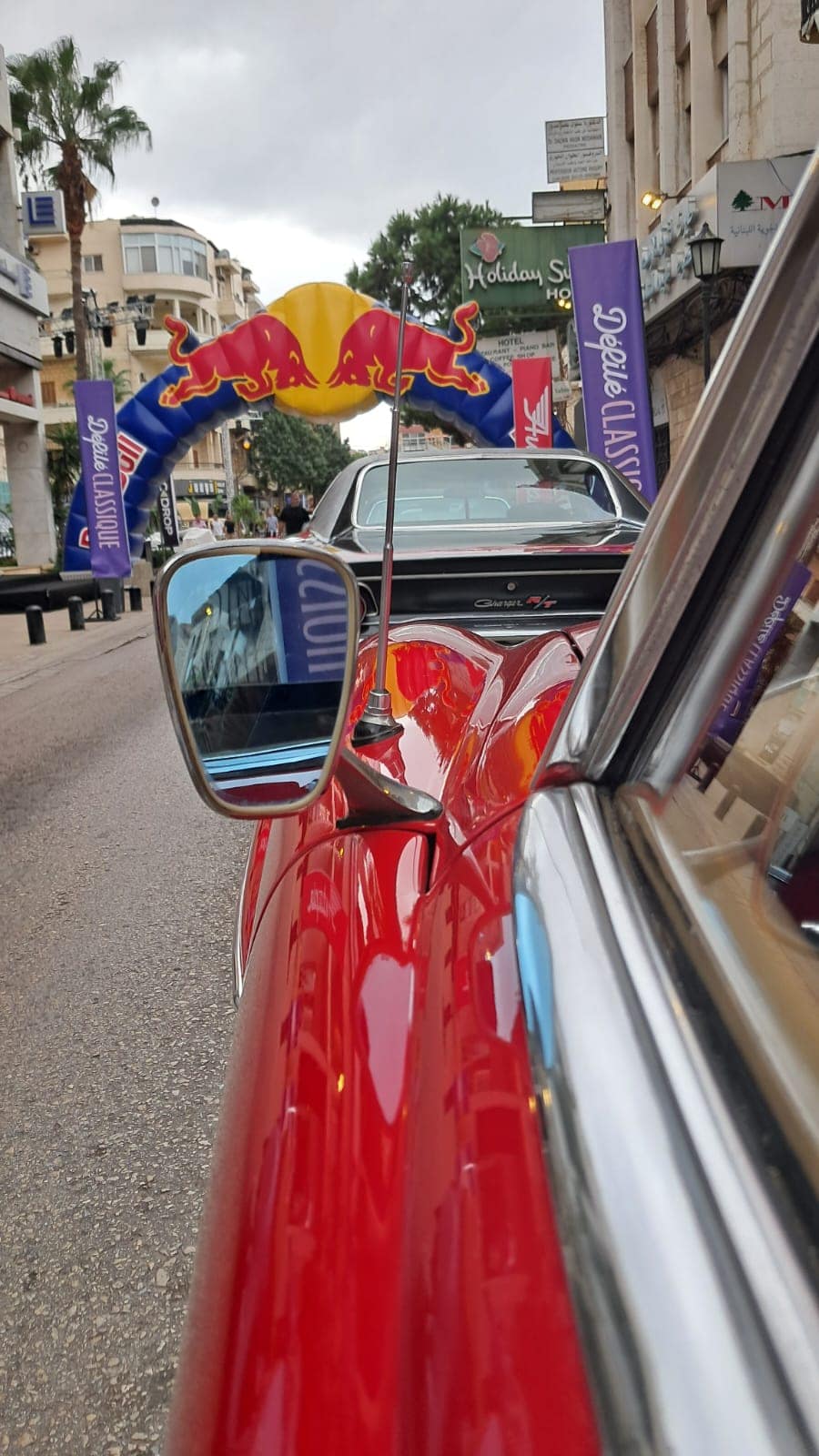 A red classic's wing mirror with the arch and the souk ahead