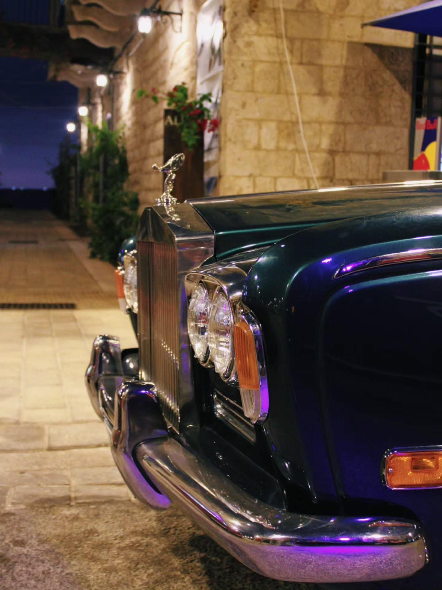 A dark Rolls-Royce in the souk at night