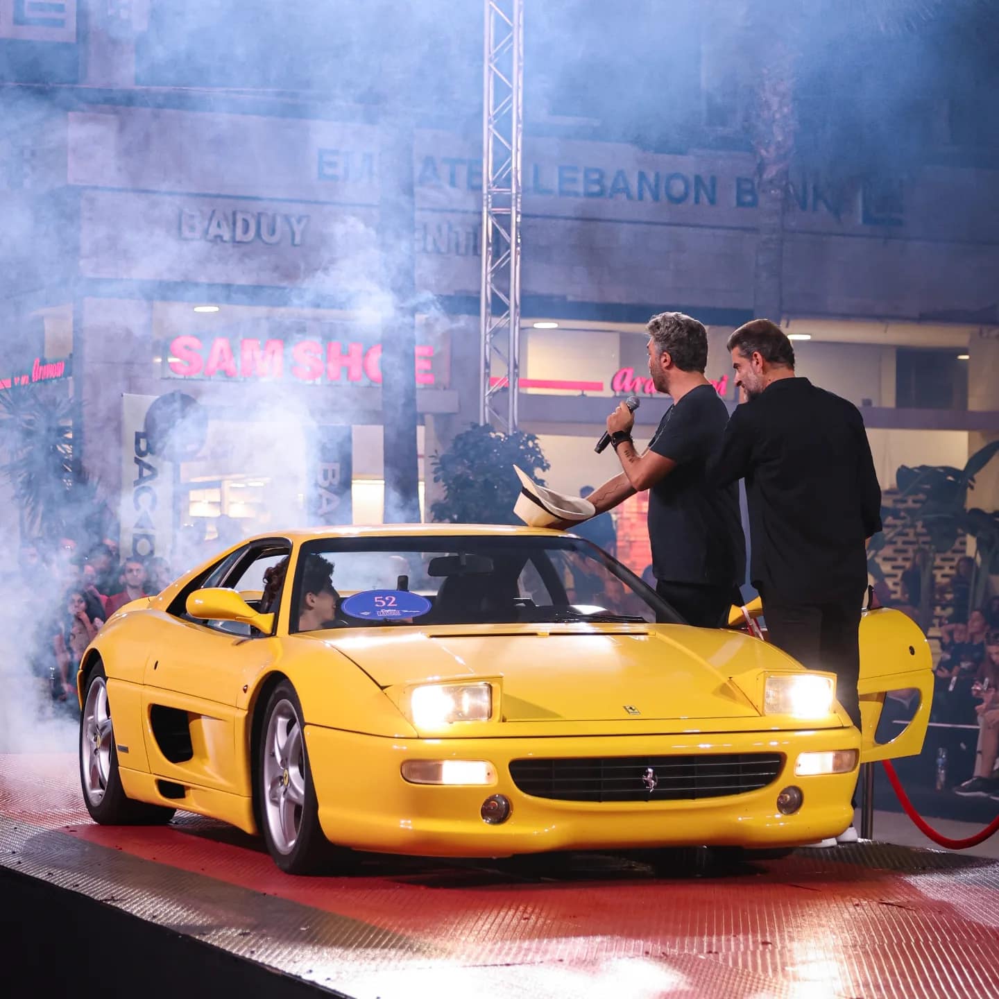 A yellow Ferrari 355 under the stage lights